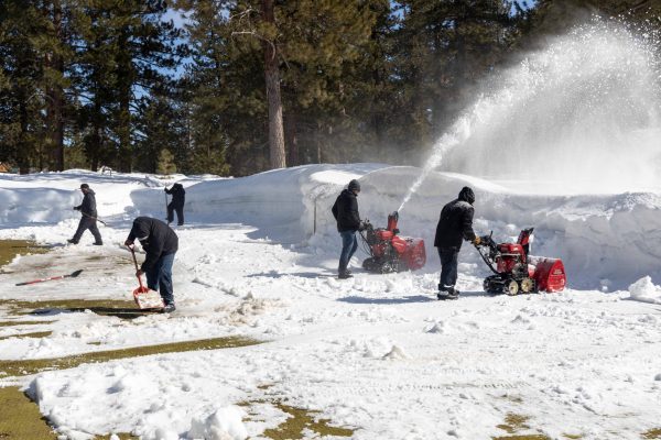 Crew of greenskeepers work to clear snow off the 9th green of Old Greenwood.