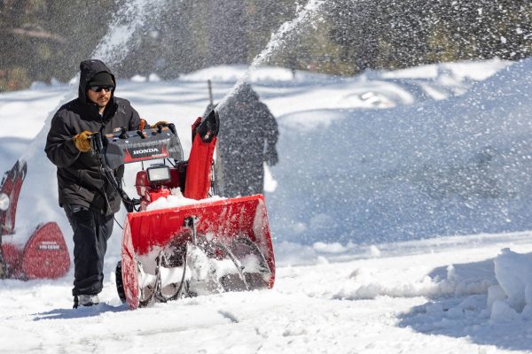 Greenskeeper Rios Gonzalez uses a snowblower to remove snow from the 9th green of Old Greenwood.