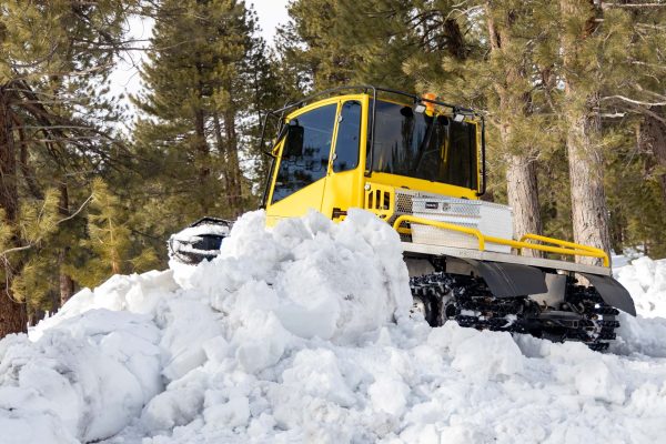 Snowcat sits atop large snow pile just beyond the  edge of the 1st green.